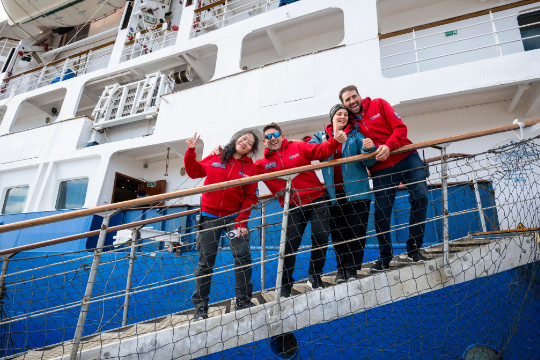 Das Expeditionsteam steht auf der Gangway und begrüßt die Gäste an Bord des Expeditions-Kreuzfahrtschiffs