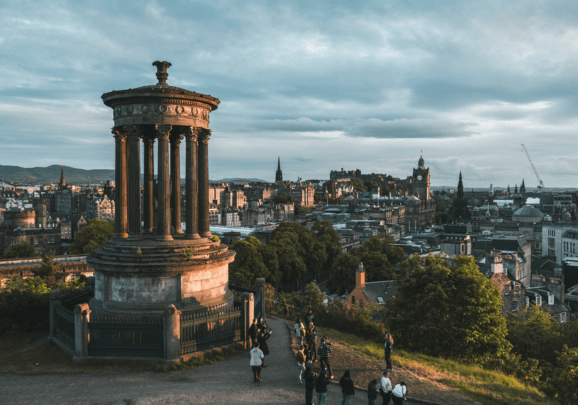 Das abendliche Edinburgh mit den Gästen der Kreuzfahrt die vor einem Monument stehen und den weiten Blick über die schottische Metropole genießen