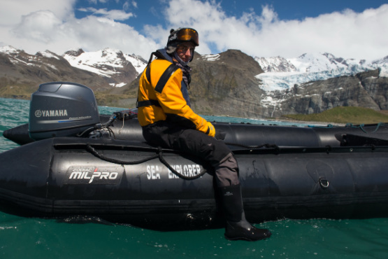Expeditionsmitglied sitzt im Schlauchboot und wartet auf seine Kreuzfahrtgäste. im Hintergrund sind schneebedeckte Berge zu sehen
