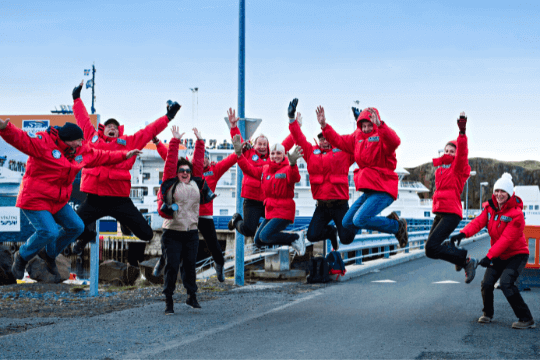 Gäste der Kreuzfahrt springen vor dem kreuzfahrtschiff iim Hafen von Ushuaia in die Luft