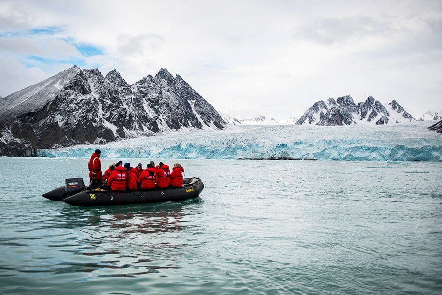 Ein Schlauchboot fährt langsam zu einem großen Gletscher in einem Fjord auf Spitzbergen
