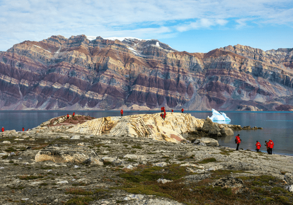 Wir wandern während der Kreuzfahrt vorbei an Bergen mit beeindruckenden Gesteinsschichten in einem Fjord in Grönland