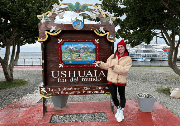 Das Ortschild von Ushuaia mit einem Kreuzfahrtgast