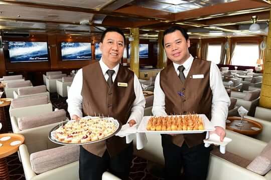 Zwei Kellner halten Tablets mit köstlichem Essen auf einem Kreuzfahrtschiff