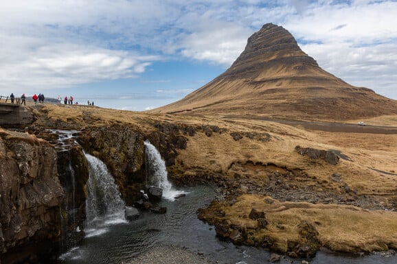 Gäste der Kreuzfahrt wandern oberhalb des Wasserfalls auf der Snæfellsnes Halbinsel mit dem Berg Kirkjufell im Hintergrund
