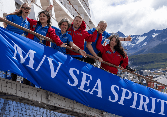 Das Expeditionsteam steht auf der Gangway und verabschiedet die Gäste von Bord des Expeditions-Kreuzfahrtschiffs