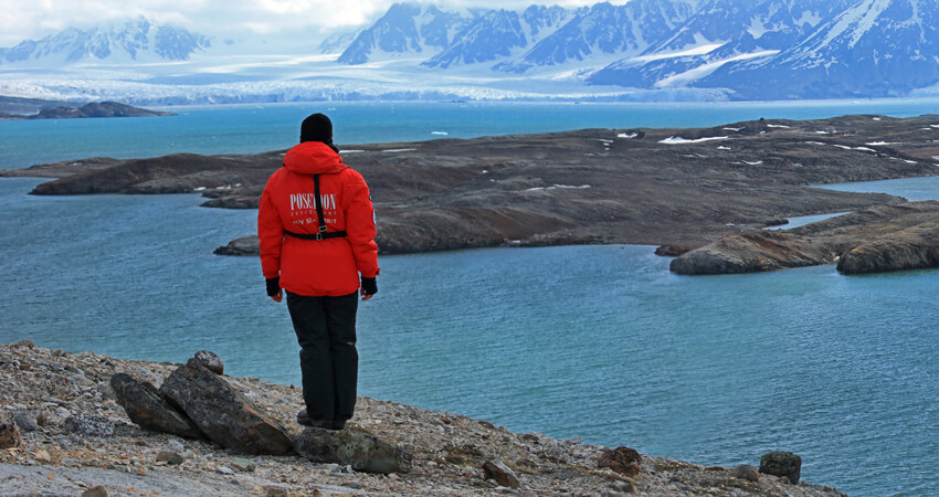 Ein Kreuzfahrtgast blickt über einen Fjord auf eine schneebedeckte Bergkulisse auf Spitzbergen Eine-Frau-erlebt-die-Polarnacht_04