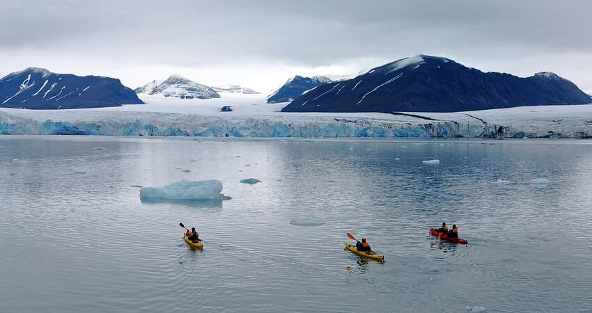 Kreuzfahrtgäste haben die Kajaks genommen und erkunden die imposanten Gletscherfronten und die treibenden Eisberge vom Svalbard-Archipel auf Spitzbergen kayaking-in-svalbard-0