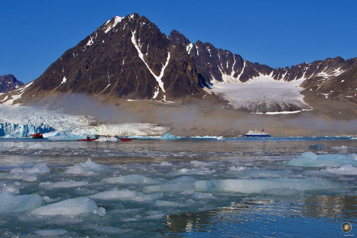 Kajakfahrer vor einem Gletscher und einem schroffen Berg mit restlichem Schnee Expeditionsreise-Spitzbergen-blog-5