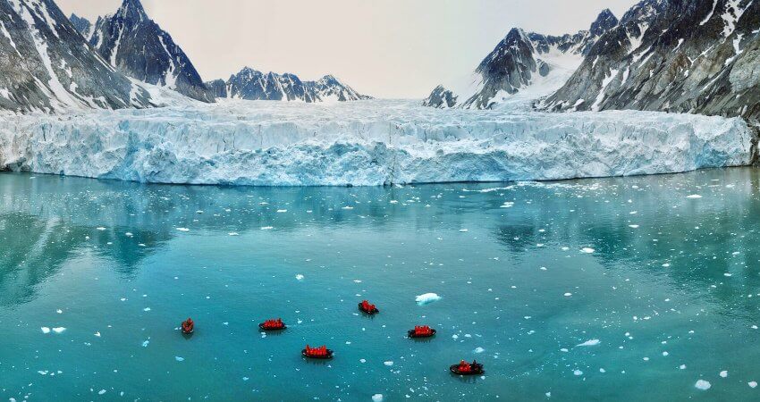 Mehrere Schlauchboote mit Kreuzfahrtgästen fahren vor einem Gletscher auf dem Svalbard-Archipel svalbard-0