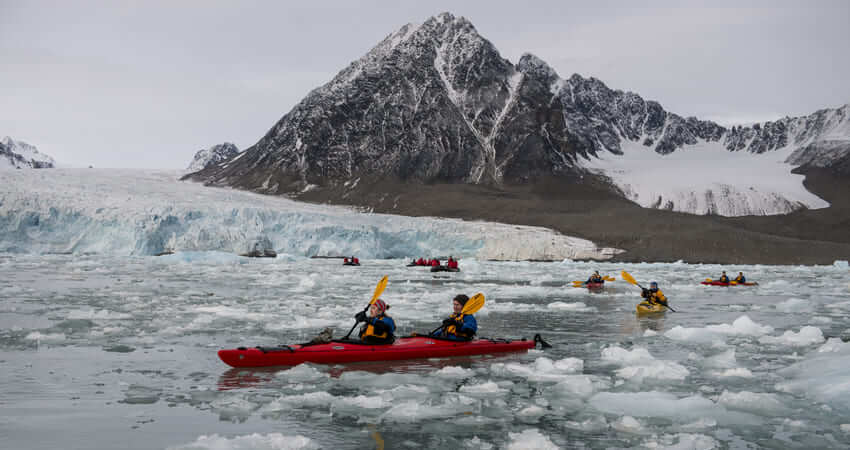 Kajaker fahren durch ein Feld von Eischollen vor einem Gletscher auf der Spitzbergen Kreuzfahrt kayaking-in-svalbard-3
