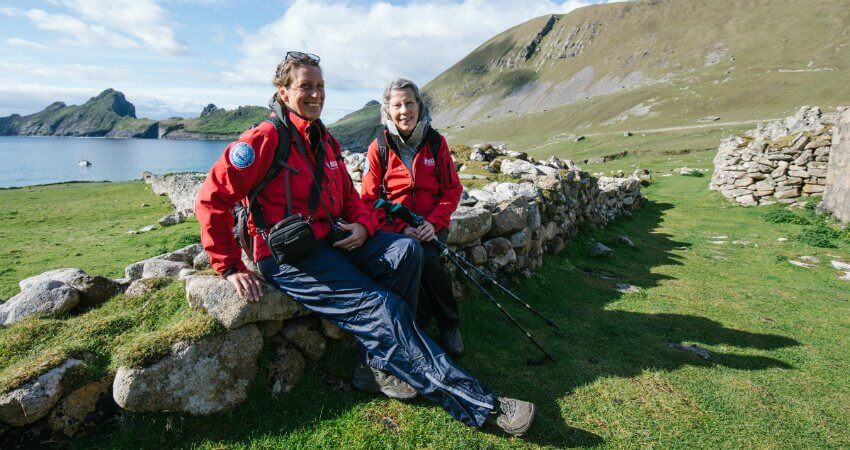 Zwei strahlende Expeditionsmitglieder, sitzend vor einem See im Hintergrund auf den Saltee Inseln top-experiences-british-isles-3