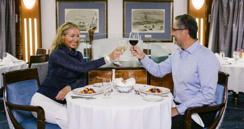 Im Restaurant des Expeditionskreuzfahrtschiffs prostet sich ein Ehepaar mit einem Glas Wein auf den Tag in Spitzbergen zu svalbard-5