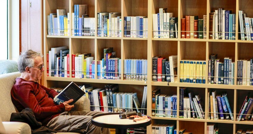 In der Bibliothek an Bord des Expeditionskreuzfahrtschiffs liest ein Kreuzfahrtgast ein Buch von dem Polarforscher Knud Rasmussen knud-rasmussen-3